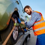Tow truck operator fixing car on platform