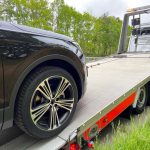 Black new SUV is pulled onto a tow truck